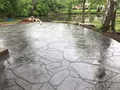 an outdoor patio is being built in the middle of a wooded area with water and trees