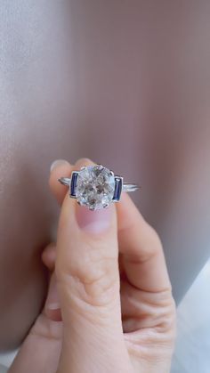 a woman's hand holding an engagement ring with a diamond in the middle and blue band around it