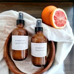 two bottles of sparkling grapefruit on a wooden bowl next to an orange