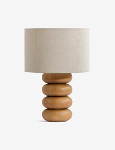 a wooden table lamp sitting on top of a white floor next to a light shade