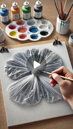 a person is painting on a canvas with watercolors and paintbrushes in front of them