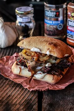 a sandwich with meat and onions on a wooden table