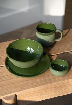 two green cups and saucers on a wooden table