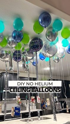 some balloons are hanging from the ceiling in a room that is decorated with blue, green and silver