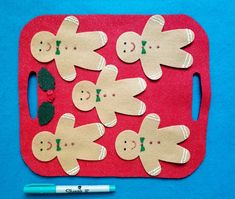 a red cutting board with cut out gingers on it next to a blue marker