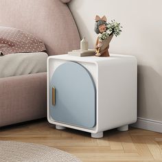 a white and blue cabinet sitting on top of a wooden floor next to a bed