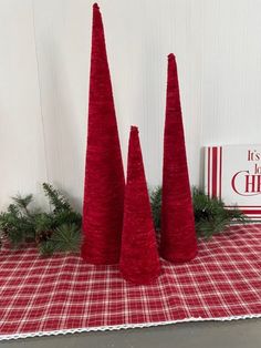 three red christmas trees sitting on top of a checkered table cloth next to a sign