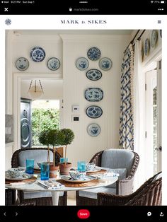 the dining room table is set with blue and white plates on the wall above it