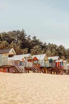 a row of beach huts sitting next to each other on top of a sandy beach