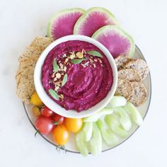 a white plate topped with fruit and veggies next to crackers