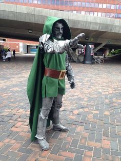 a man dressed in costume standing on a brick walkway with his hand out to the side