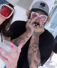 a man and woman with tattoos on their arms are holding drinks in front of them