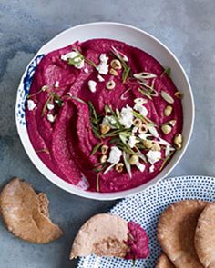 a bowl of beet hummus and pita chips on a blue tablecloth