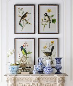 three framed pictures hang above a mantle with vases and flowers