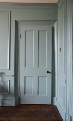 an empty room with white walls and wooden floors is pictured in this image, the door has been painted pale blue