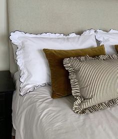 a bed with white sheets and brown pillows