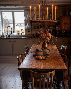 a wooden table sitting in the middle of a kitchen with candles on top of it