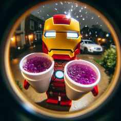 two cups filled with purple liquid sitting on top of a table next to a lego iron man figure