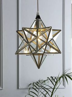 a star shaped light hanging from the ceiling next to a potted plant and door