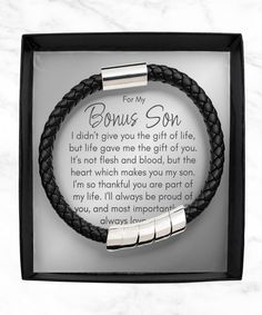 a black leather bracelet with two stainless steel bar clasps and an inscription on it