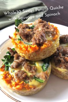 three mini quiches with sausage and spinach are on a white plate next to a green napkin