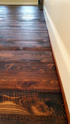 a wooden floor with white trim and brown stain on the top part, in front of an open door