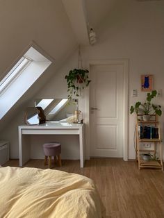 a bedroom with a bed, desk and mirror in it's corner under a slanted roof