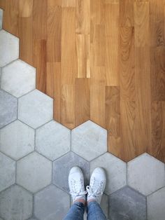 a person standing on top of a wooden floor next to a white and gray tiled floor