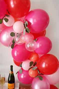 a bunch of balloons that are next to a wine glass and bottle on a table