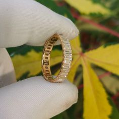 a person holding a ring in their hand with leaves behind it and the background is green