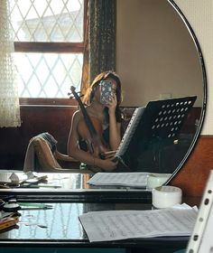 a woman sitting at a desk in front of a mirror holding a cell phone to her ear