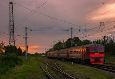 a train traveling down tracks next to power lines and telephone poles in the evening sky