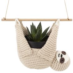 a stuffed animal hanging from a wooden hanger with a potted plant in it