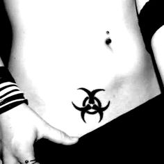 a woman's stomach with a biohazard tattoo on her left side belly