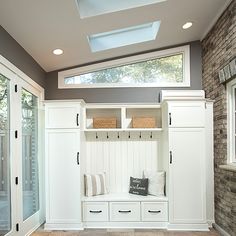 a room with some white cabinets and pillows on it's shelfs in front of a window