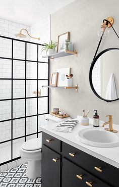 a white bathroom with black and gold accents