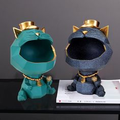 two cat figurines sitting on top of a black table next to each other