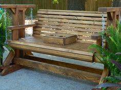 a wooden bench sitting in the middle of a yard next to some plants and trees