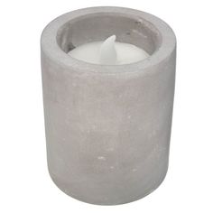 a concrete candle holder with a single white candle in it's center, on a white background