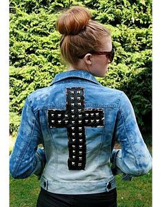 a woman wearing a jean jacket with a cross on it