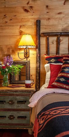 a bed in a bedroom next to a wooden dresser with a lamp on top of it