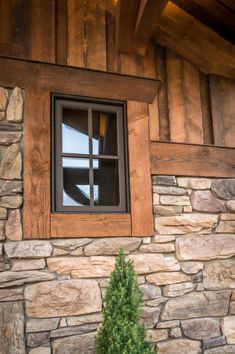 a window on the side of a stone building with a potted plant next to it