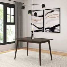 a dining room table with two paintings on the wall above it and a rug underneath