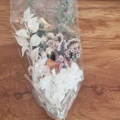 a bouquet of flowers wrapped in plastic on top of a wooden table