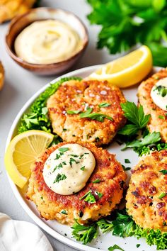 several crab cakes on a plate with lemon wedges and parsley garnish