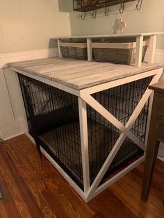 a dog crate sitting on top of a hard wood floor next to a wooden table