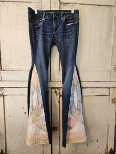 a pair of blue jeans with patchwork on them hanging from a hook in front of an old door