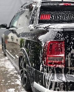 the back end of a black pickup truck covered in foamy water and sprays