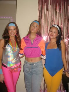 three young women standing next to each other in front of a wall with pink and blue curtains