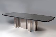 a black table sitting on top of a white floor next to a gray wall in the background